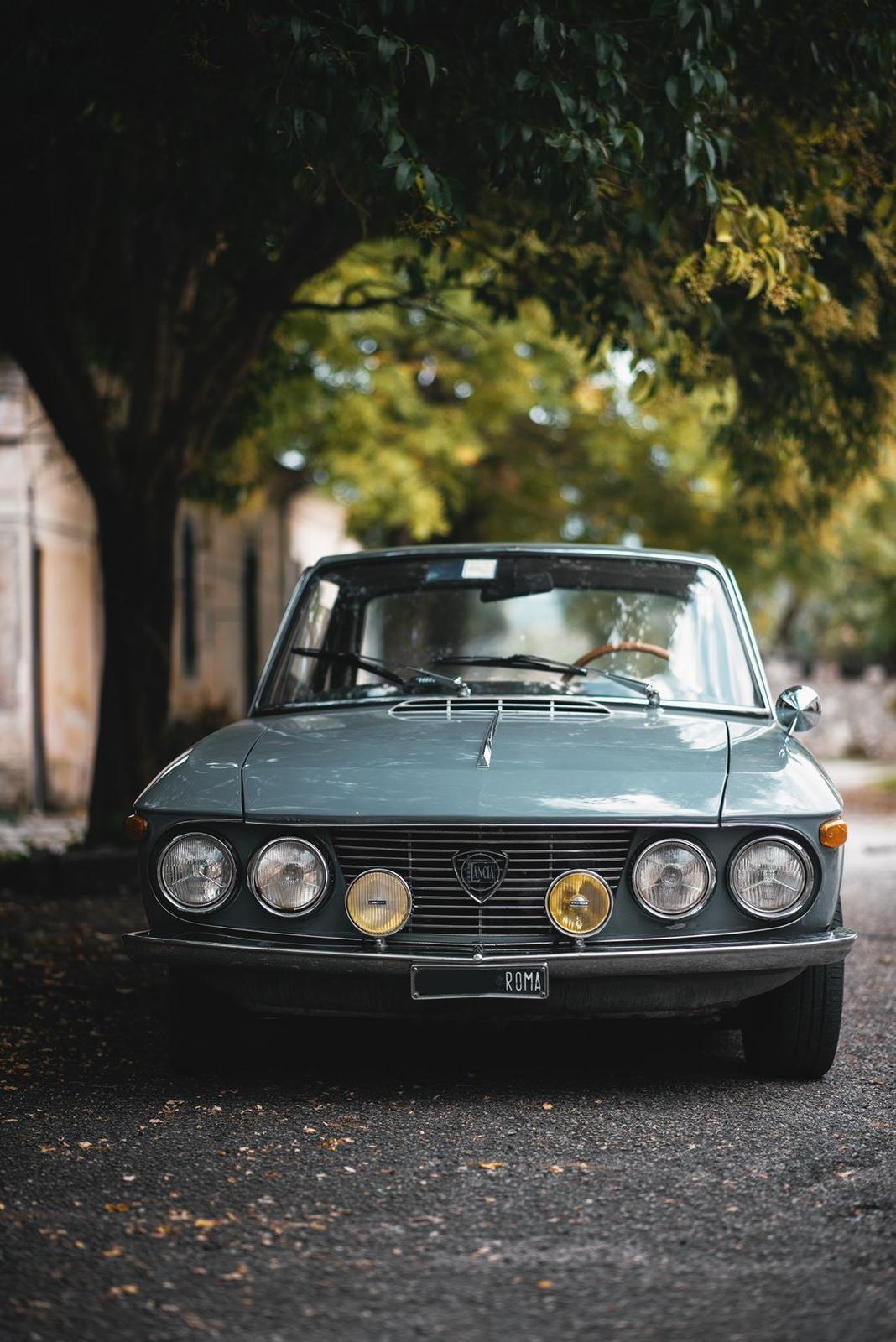 Lancia Fulvia Coupé d'epoca grigio fumo, frontale sotto l'albero